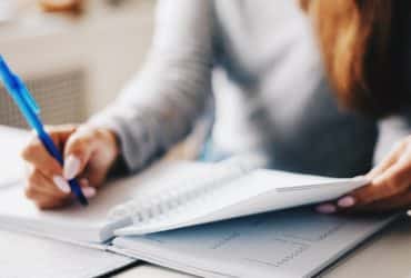 woman at desk writing in notebook