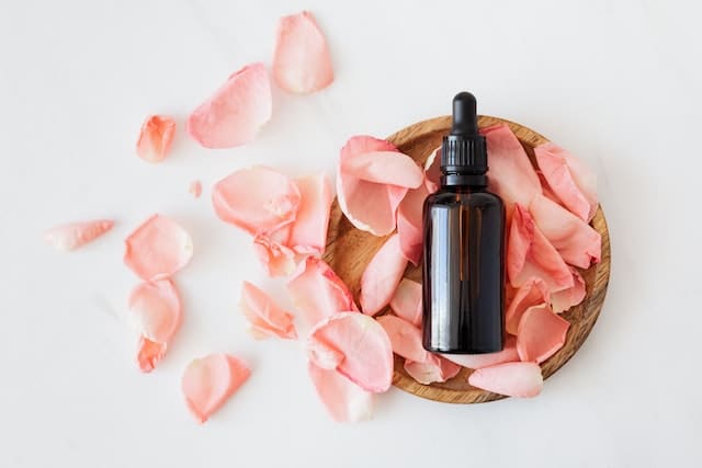 Rose oil bottle on top of rose petals