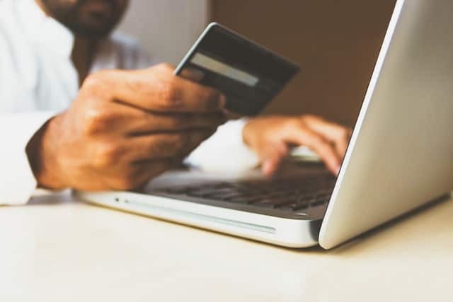 man holding credit card while working on a laptop