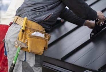 construction worker applying metal roofing to house