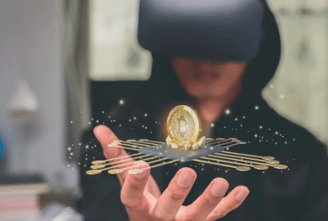 man with VR goggles looking at a bitcoin floating above his hand