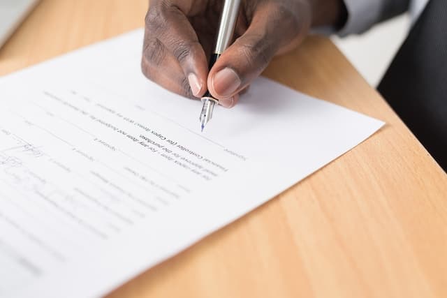 man's hand signing a contract