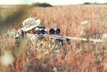 Hunter with rifle laying down to shoot