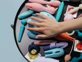 person's hand choosing from a number of sex toys on a table