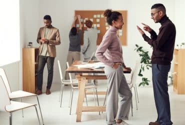 group of people standing in a conference room discussing something