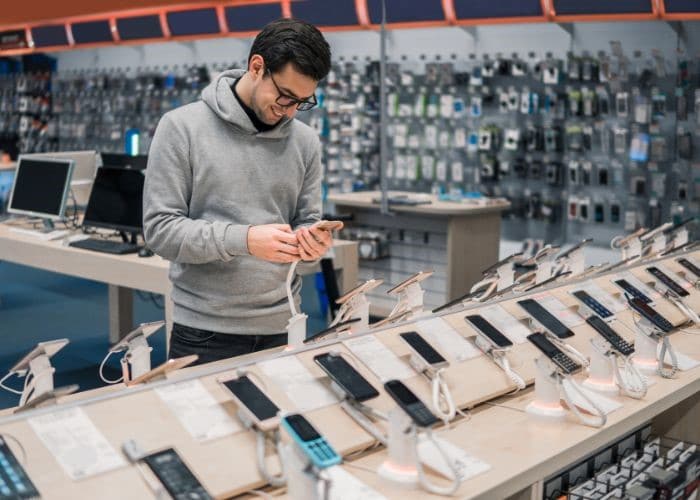 man shopping for new smartphone and looking at a rack of different phones