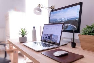 laptop and monitor on desk showing a web page design in progress