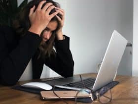 teen holding their head in their hands while staring at laptop screen