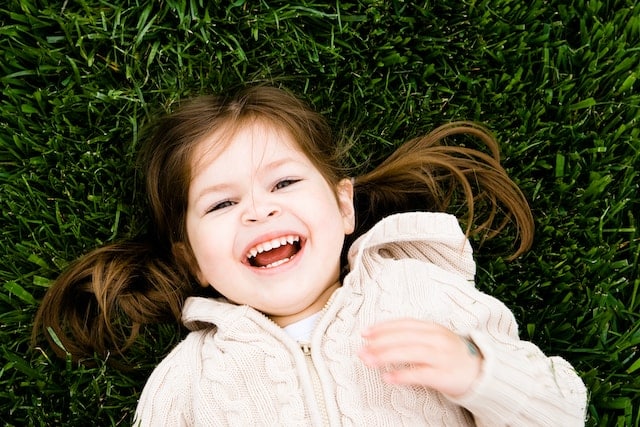 little girl laying in the grass with a big smile