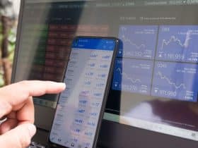 man working on phone that is set against computer monitor