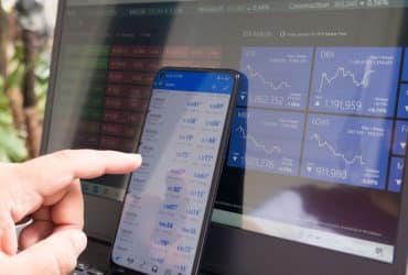 man working on phone that is set against computer monitor