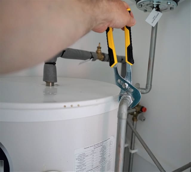 man fixing pipe connected to a hot water heater