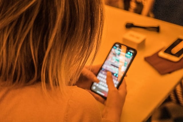 woman texting on her phone while sitting at a table