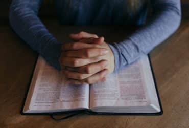 man praying over an open Bible