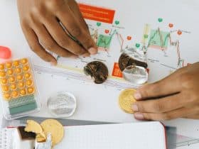 hands of a person doing financial analysis with a calculator and chocolate coins
