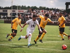 4 soccer players running with the ball in the middle of a game.