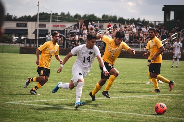 4 soccer players running with the ball in the middle of a game.