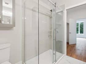 glass shower stall in a bright bathroom connected to a closet and bedroom
