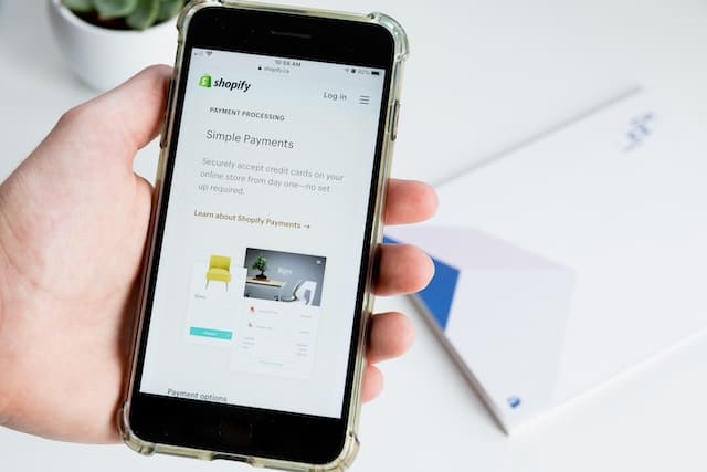 person holding a smartphone with the shopify website on the screen