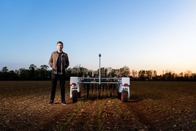 man standing next to automated, robotic farming tool