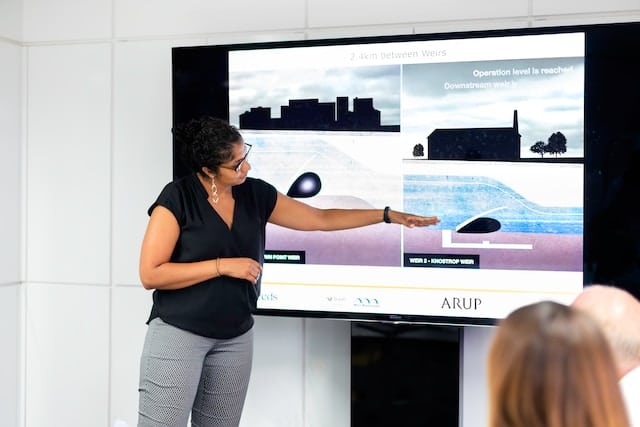 woman giving a presentation using a shared screen on a TV in a conference room