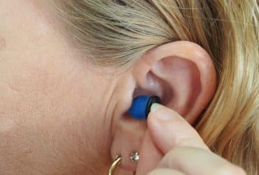 woman touching a hearing aid in her ear