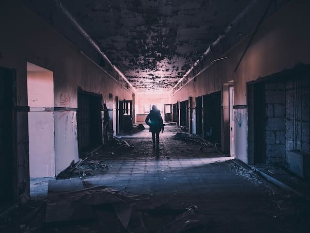 person walking through a hallway after the building was destroyed by flood damage