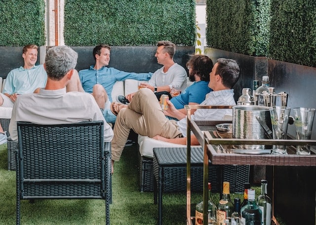 a group of men enjoying drinks in a backyard patio area