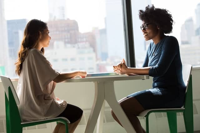 two professional women talking over a small table