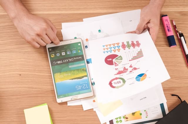 person looking at a tablet while examining categorized data