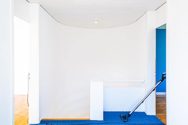 vacuum cleaner entering a small, carpeted room that is painted white