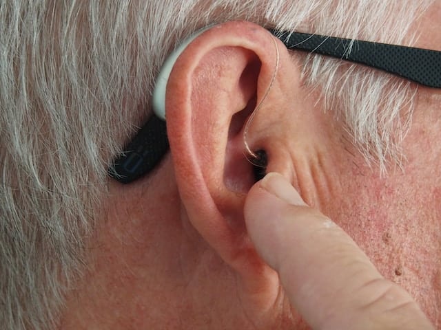 man wearing a hearing aid and making an adjustment to it