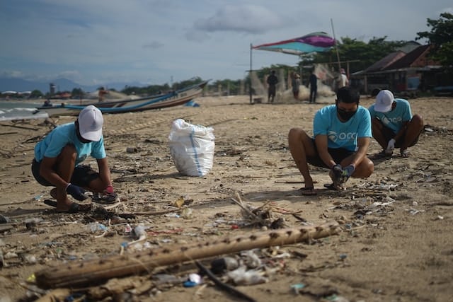 people working to clean up a beach from trash and debris