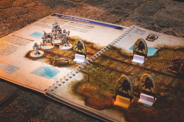 Gloomhaven: Jaws of the Lion role-playing game, with the play book open and figured in play