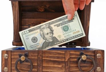 cash being placed into a wooden lockbox