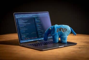 laptop with a blue, plush elephant with the label PHP on it.