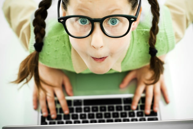 Above view of a girl geek . She is using her laptop and looking at the camera.  