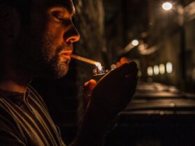 man lighting cigarette outside at night