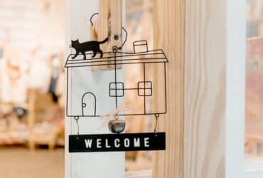 metal welcome sign with a cat on top