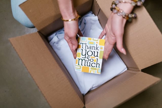 woman opening a box with a thank you note in it from the vendor