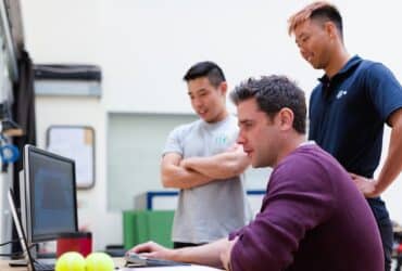 3 men gathered around a computer in a manufacturing office