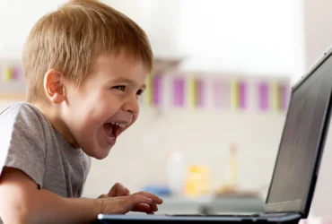 boy laughing at a game on his laptop