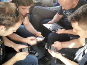 a group of guys sitting and playing a game together on their devices