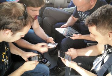 a group of guys sitting and playing a game together on their devices