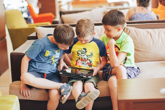 boys sitting on a couch using a tablet to play games for learning