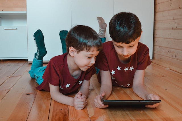 brothers using a tablet on the floor at home
