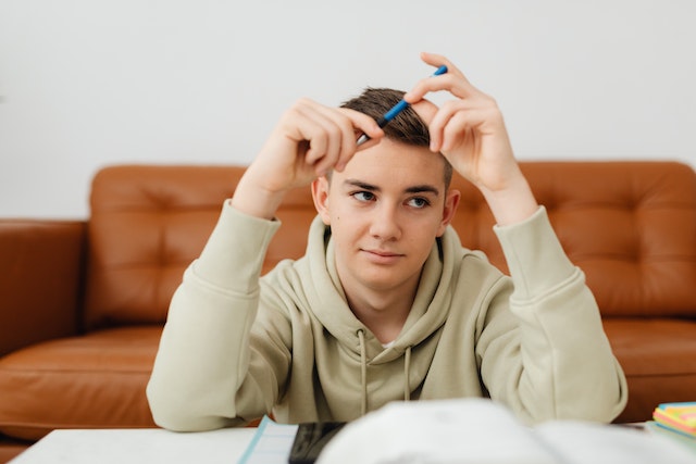 young man with a pencil seeming stumped at some of his homework