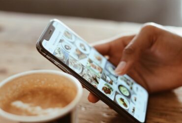 a woman drinking coffee while looking at pictures on her phone