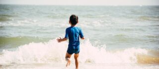 boy running into the waves at a beach