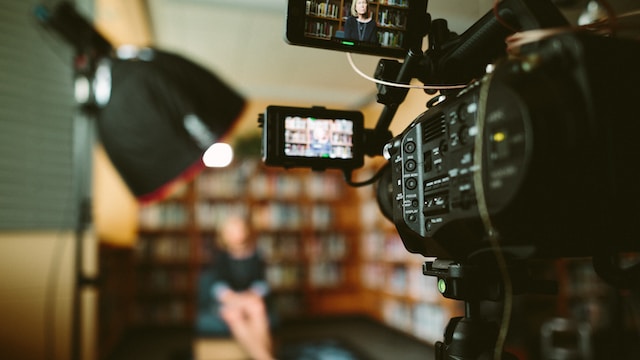 video recording of a woman speaking while sitting in a library